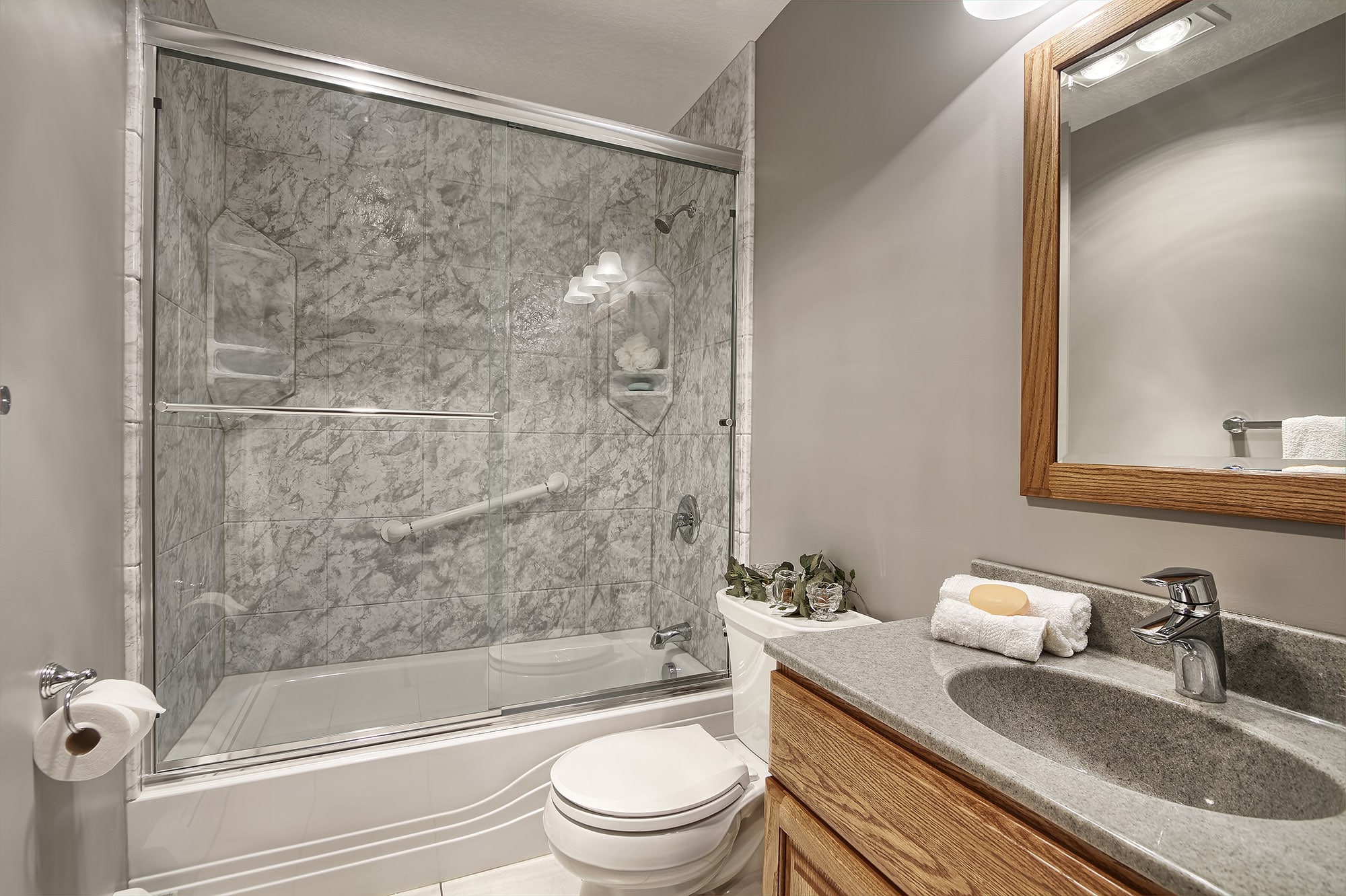 Newly installed bathtub with a marble-pattern surround and sliding glass doors