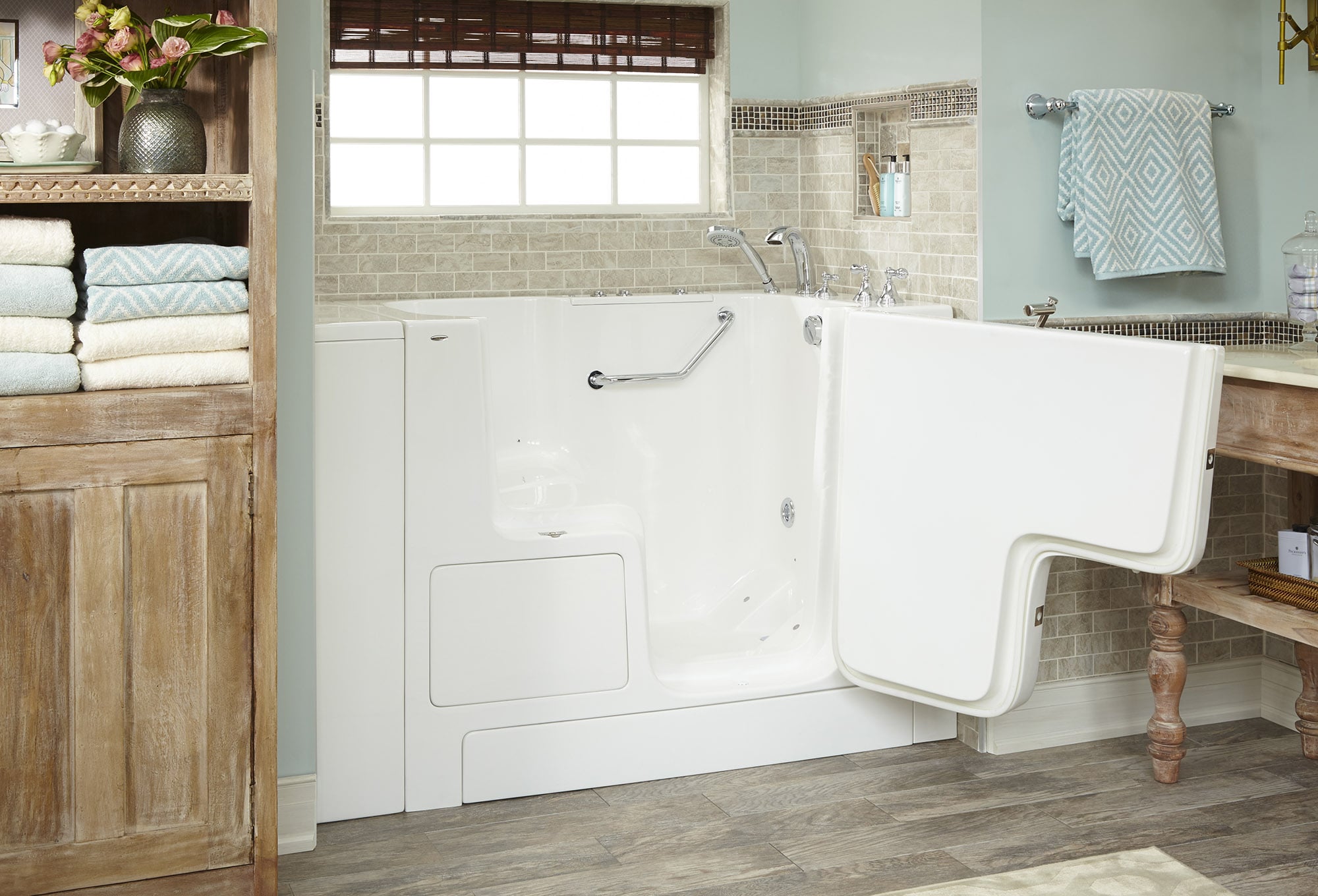 Walk-in bathtub with an open sealed door, grab bar and handheld shower fitting