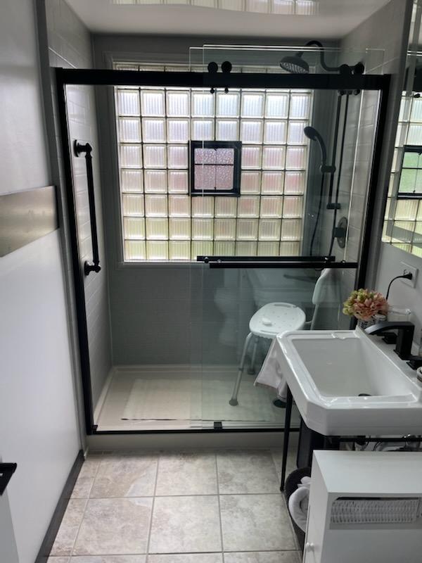 Finished tub-to-shower conversion with glass enclosure and built-in shelving